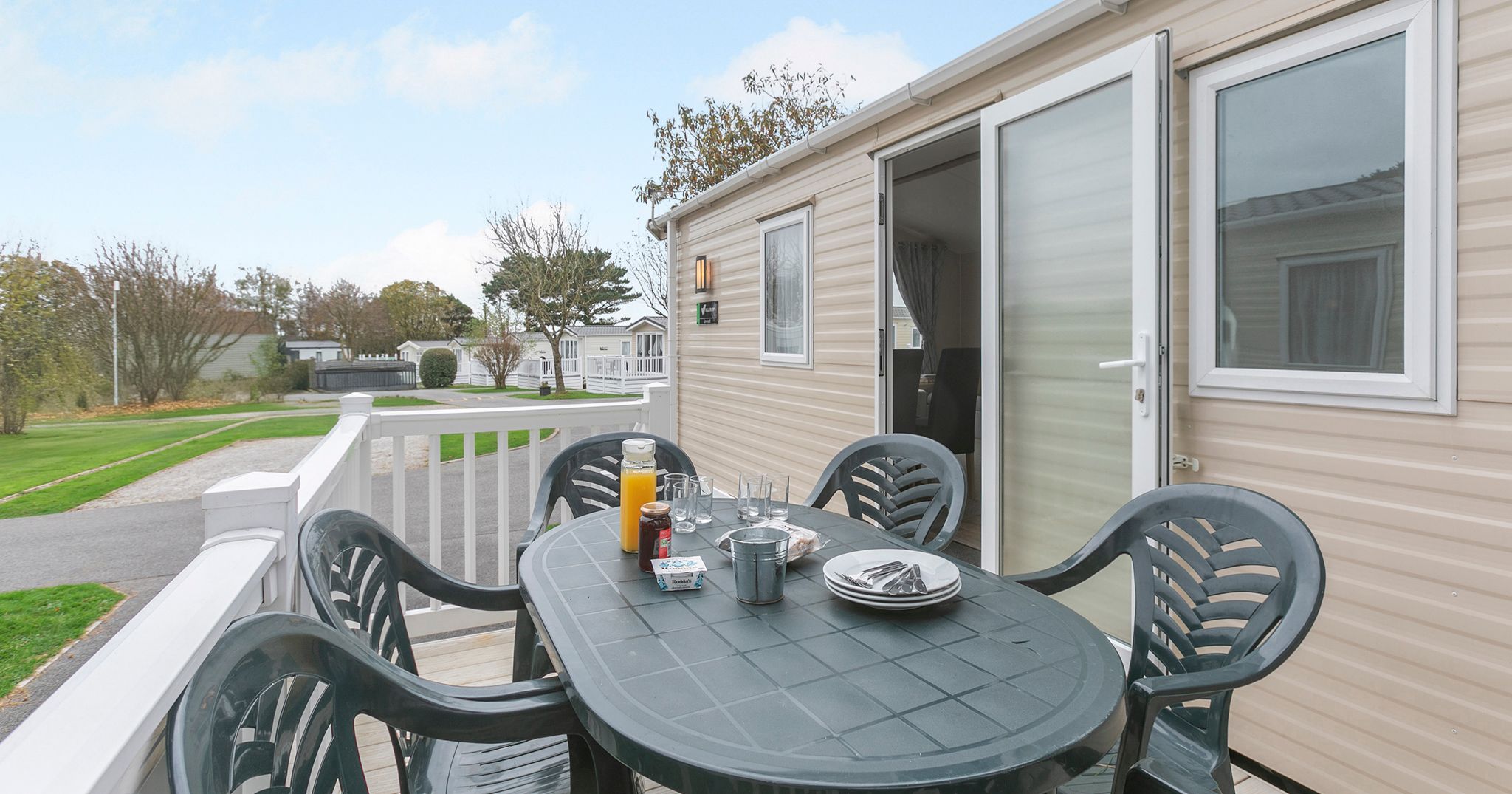 Outdoor table with chairs and breakfast items on the deck of a mobile home.