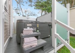 Outdoor hot tub with folded towels, champagne, and glasses on steps.