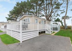 Modern mobile home with large white fenced deck and outdoor hot tub
