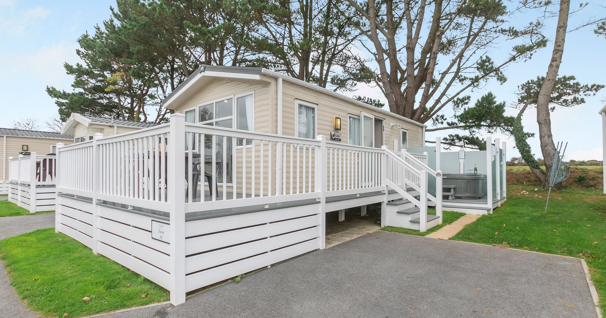 Modern mobile home with large white fenced deck and outdoor hot tub