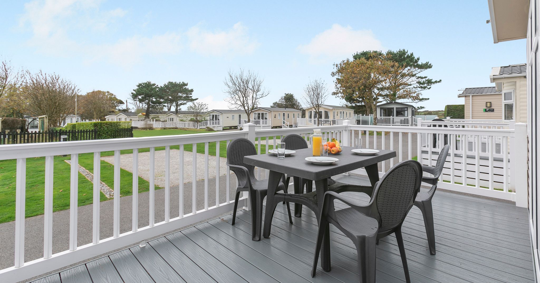 Outdoor deck with table and chairs at a holiday park with mobile homes