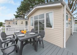 Outdoor dining area on the deck of a modern beige mobile home