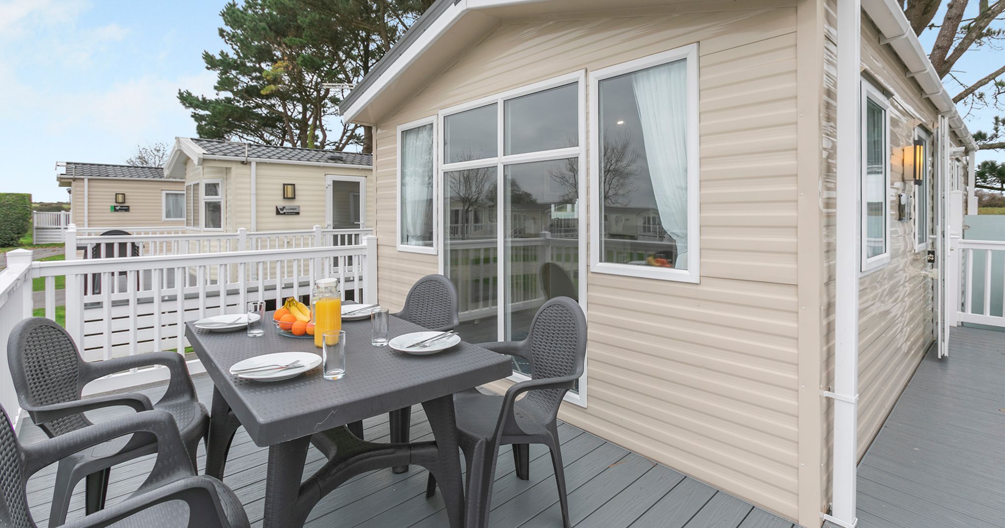 Outdoor dining area on the deck of a modern beige mobile home