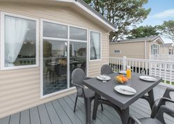 Outdoor dining setup on the deck of a modern mobile home