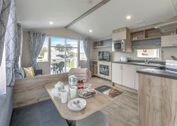 Modern holiday caravan interior with open kitchen, dining area, and living space