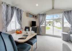 Modern mobile home interior with dining area, large windows, and living space.