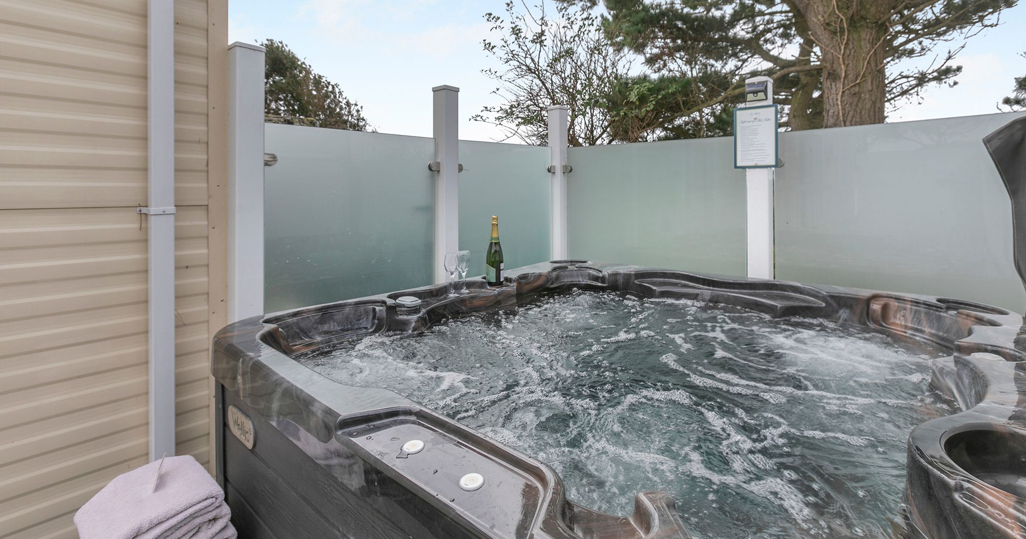 Outdoor hot tub with bubbling water, champagne bottle, and glasses