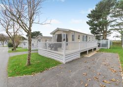 Modern mobile home with a deck and white railing in a holiday park setting.
