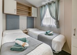 Modern twin bedroom with two single beds, folded towels, and calming decor.