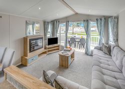 Modern holiday home living room with large windows, light decor, and outdoor patio view