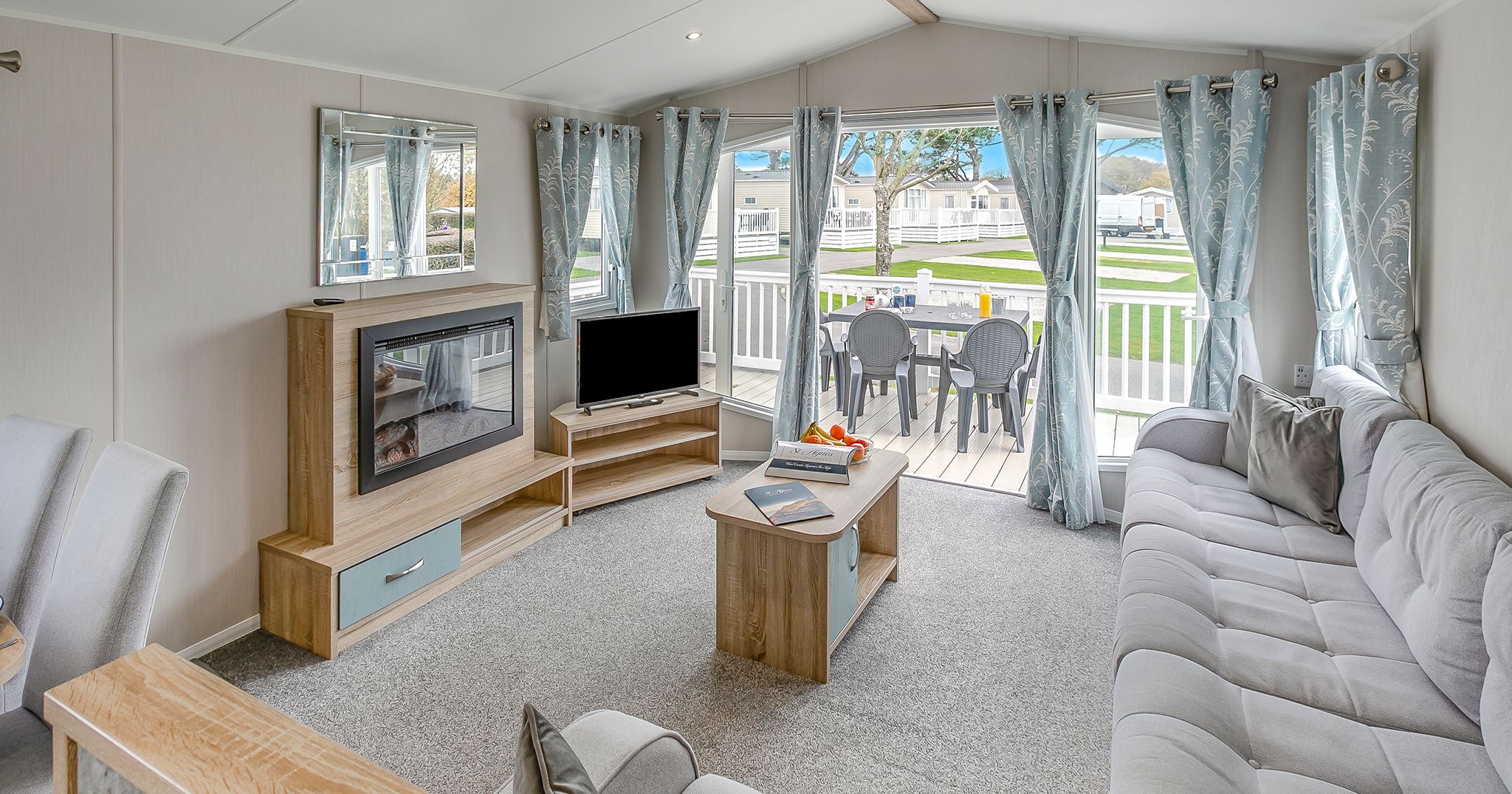 Modern holiday home living room with large windows, light decor, and outdoor patio view