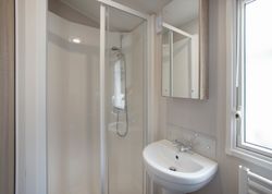 Modern compact bathroom with shower, sink, and mirror