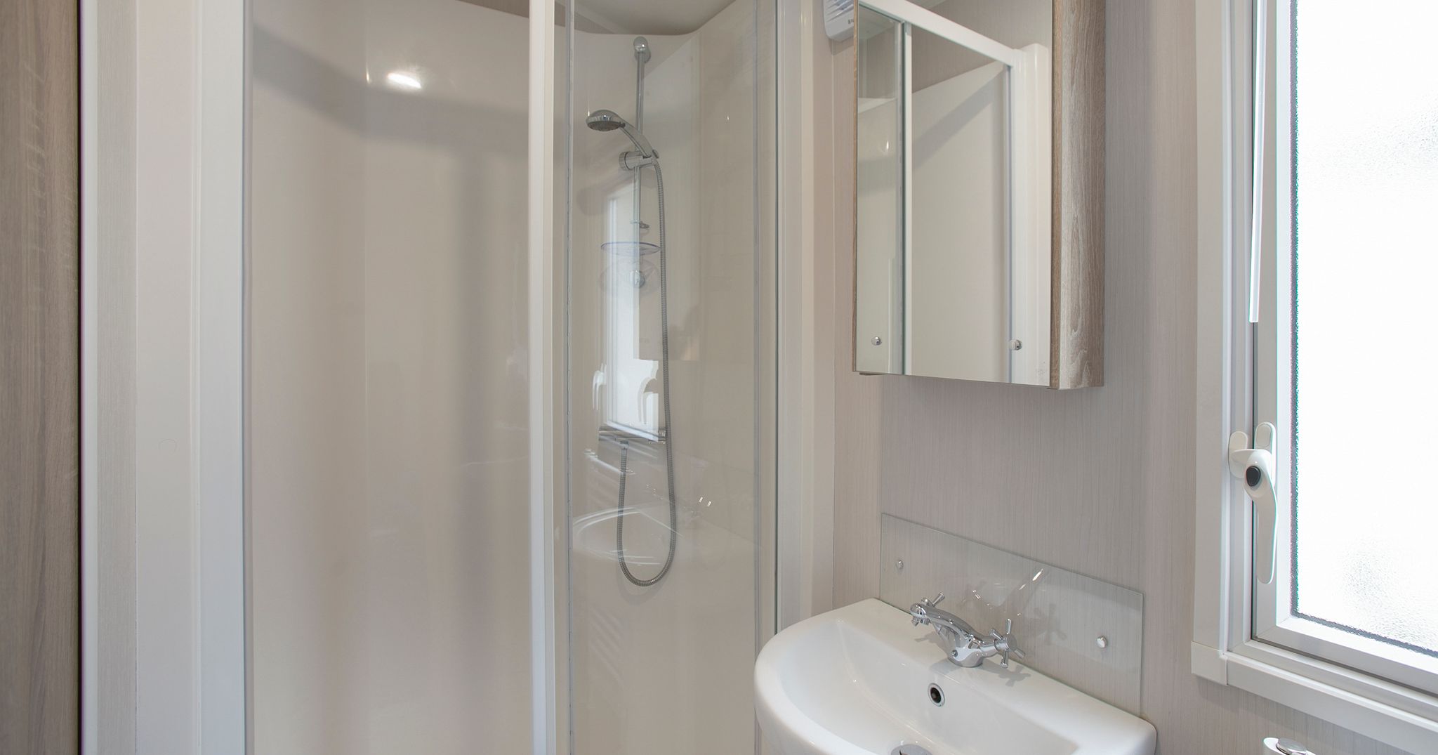 Modern compact bathroom with shower, sink, and mirror