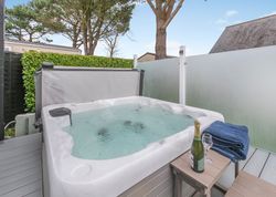Outdoor hot tub with bubbling water, champagne, glasses, and towels on a table nearby