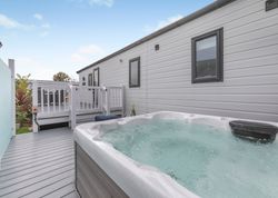 Outdoor hot tub on a deck next to a modern mobile home.