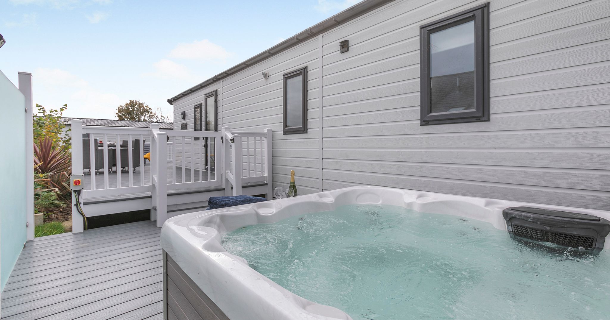 Outdoor hot tub on a deck next to a modern mobile home.