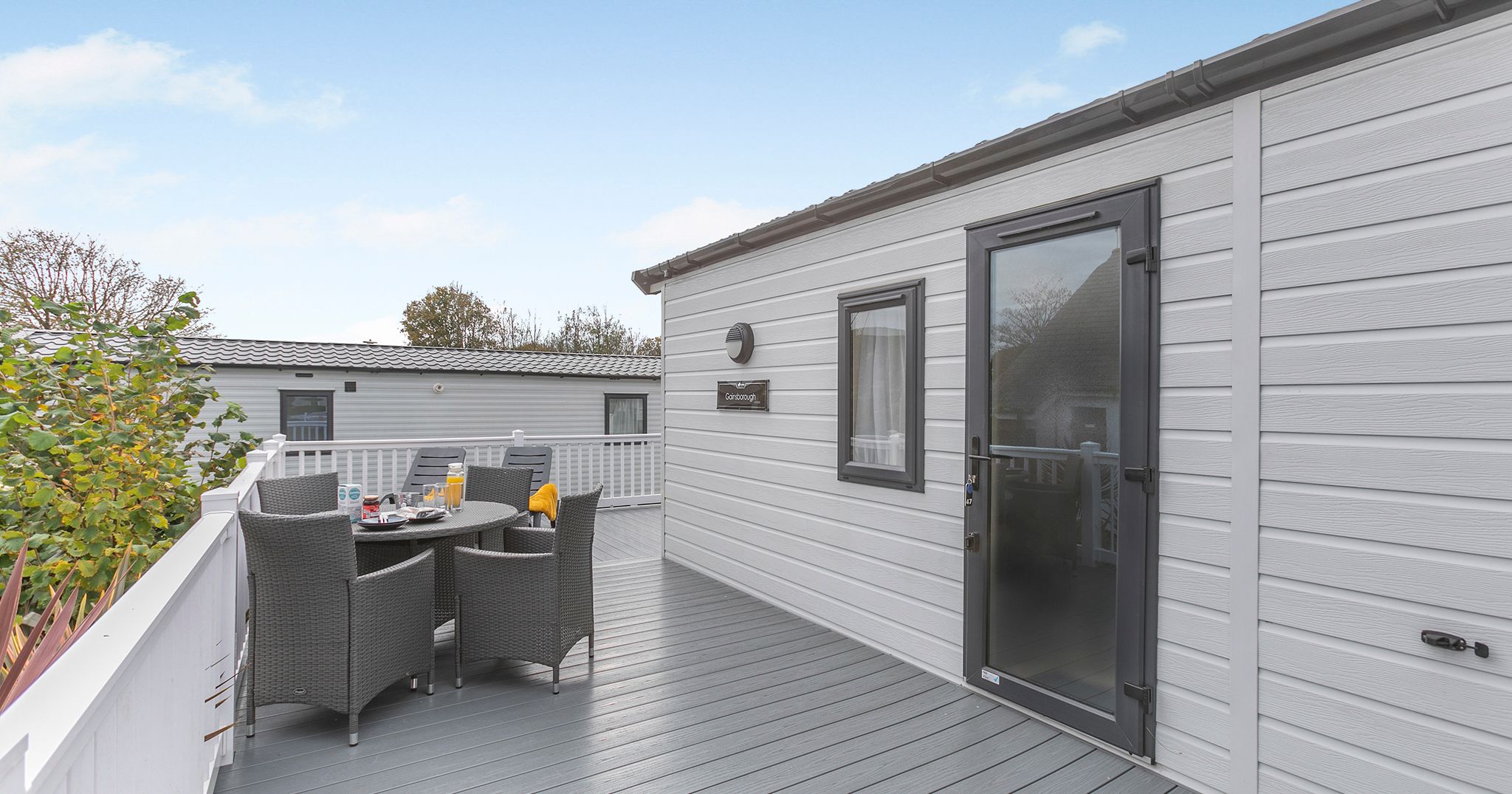 Modern holiday home with outdoor dining area on a wooden deck.