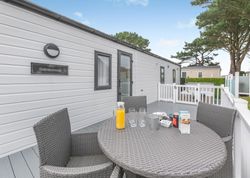 Outdoor seating area on the deck of a modern mobile home with a table set for breakfast.