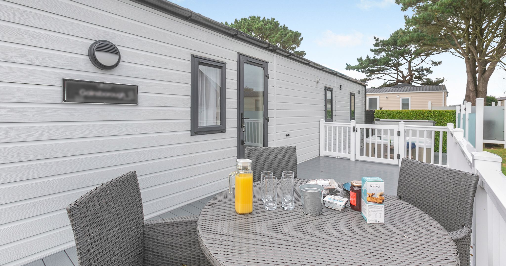 Outdoor seating area on the deck of a modern mobile home with a table set for breakfast.