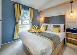 Modern bedroom with a large bed, yellow curtains, and stylish lighting