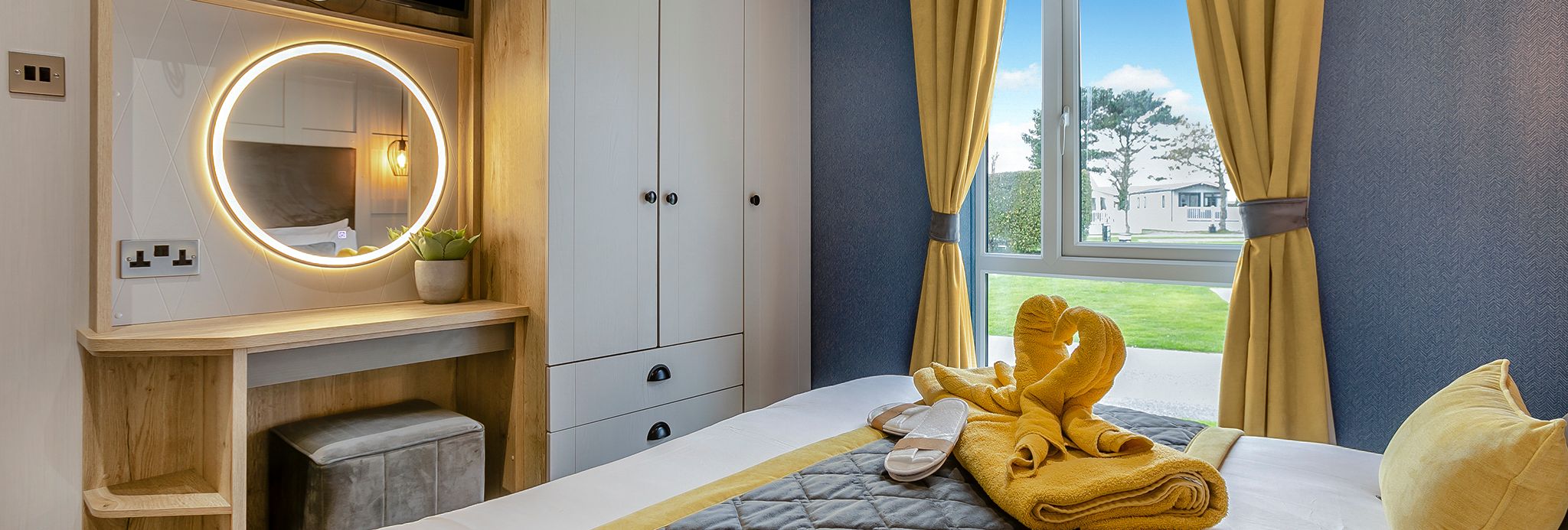Modern bedroom with yellow and gray decor, a bed, vanity, wardrobe, and window with yellow curtains.