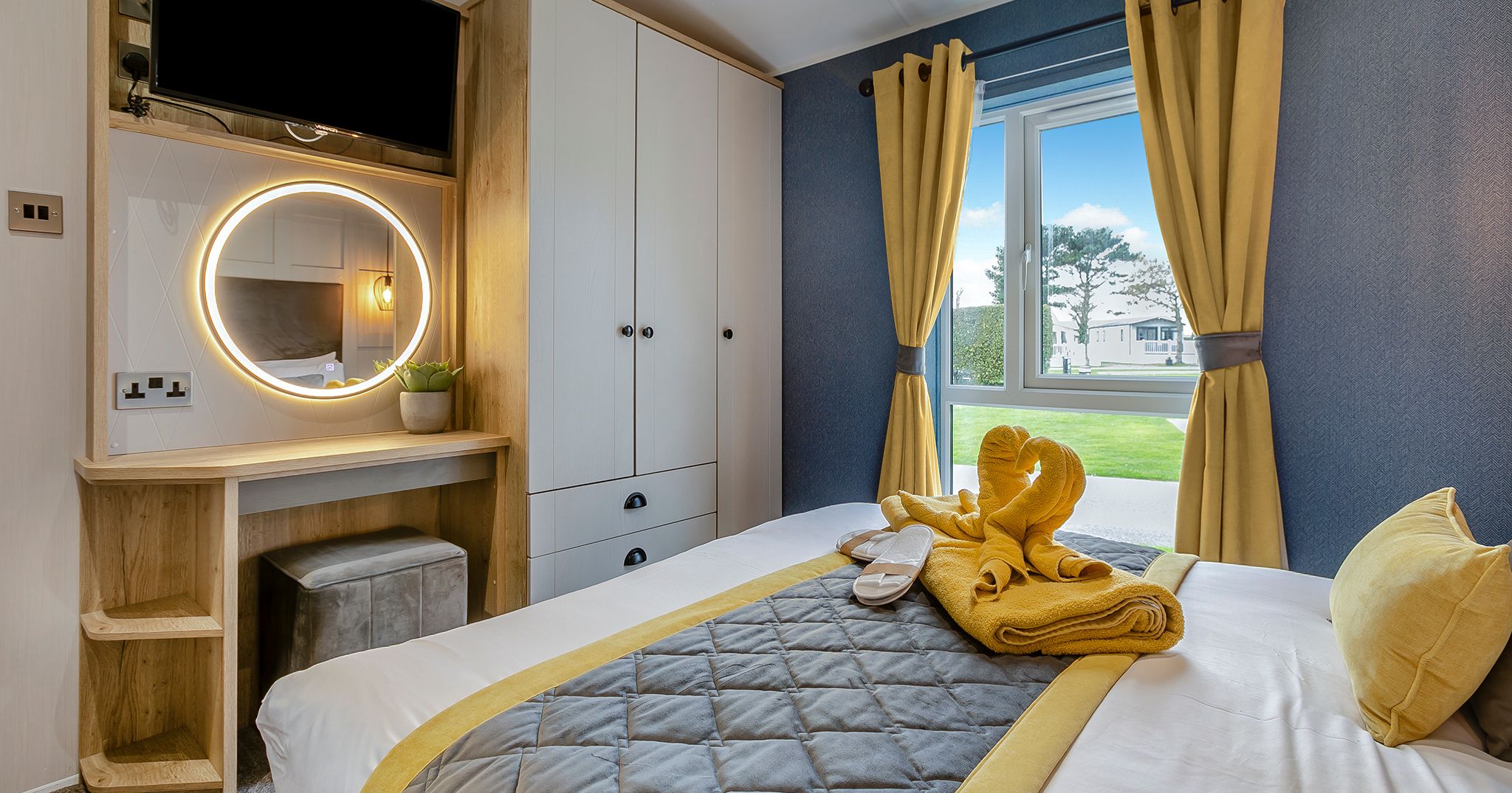 Modern bedroom with yellow and gray decor, a bed, vanity, wardrobe, and window with yellow curtains.