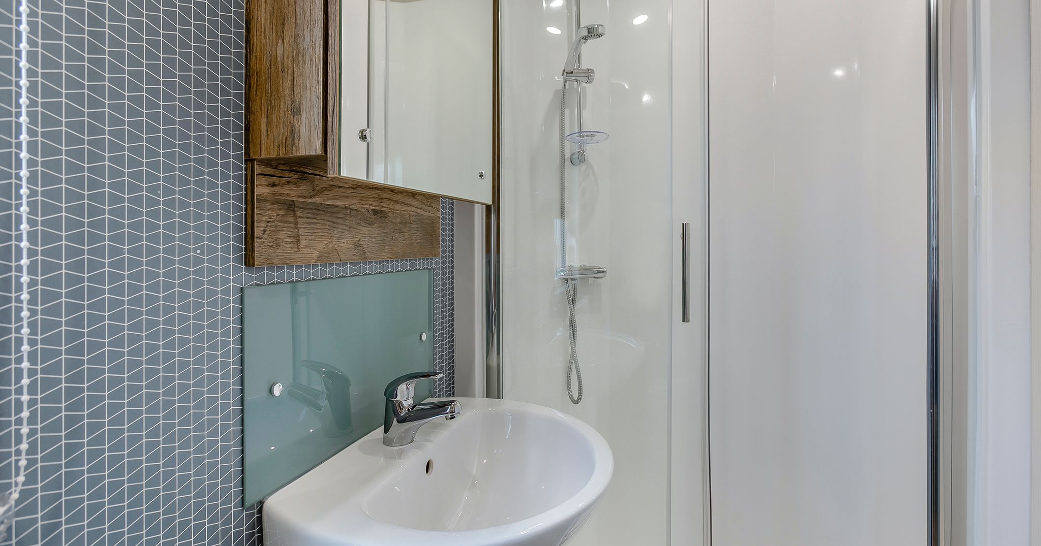Modern bathroom with sink, mirror cabinet, and glass shower enclosure