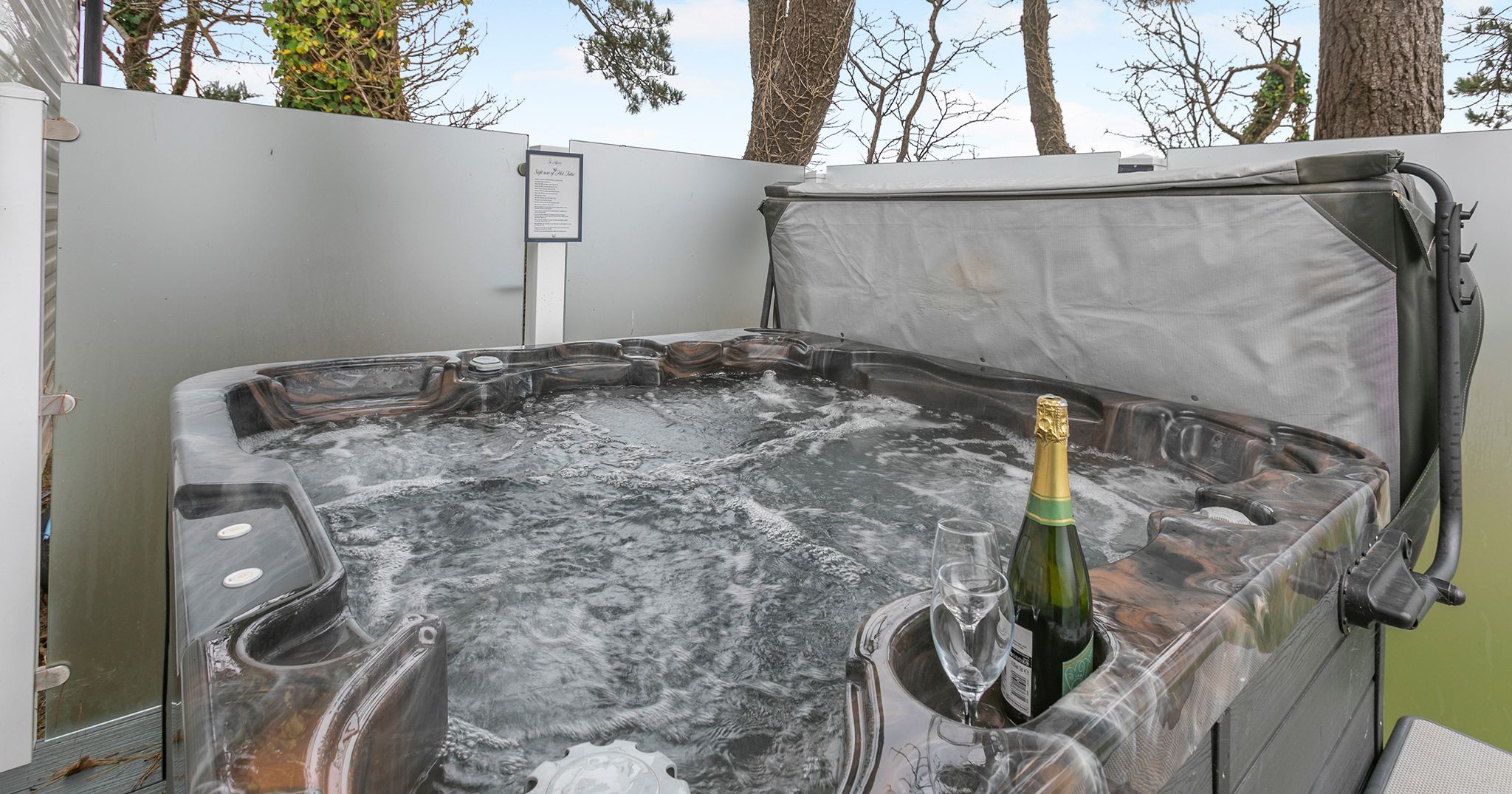 Outdoor hot tub with bubbling water, a bottle of champagne, and a glass