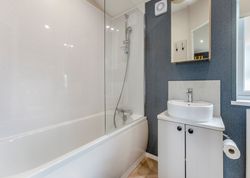 Modern bathroom with bathtub, shower, sink, mirror, and window