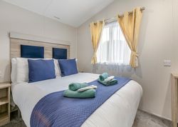 Modern bedroom with neatly made bed, blue pillows, and yellow curtains