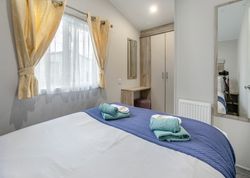 Modern bedroom with a neatly made bed, yellow curtains, and a closet