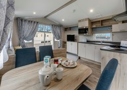 Modern mobile home kitchen and dining area with breakfast setup on the table.