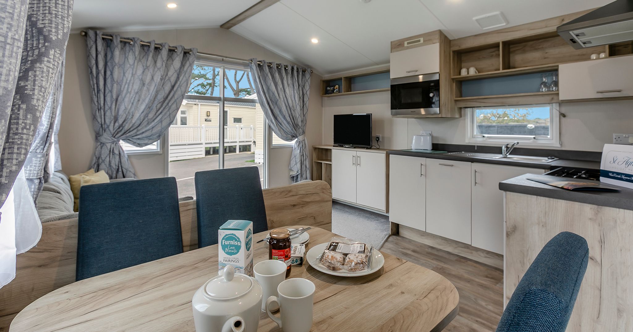 Modern mobile home kitchen and dining area with breakfast setup on the table.