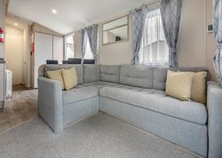 Modern living room with a large grey sectional sofa, yellow cushions, and natural light from windows with patterned curtains.