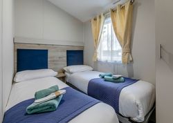 Twin bedroom with two single beds, blue headboards, and yellow curtains