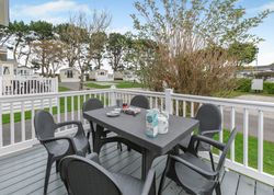 Outdoor deck with black table and chairs, set for breakfast, overlooking holiday park with mobile homes.