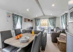 Modern living and dining area with grey furniture, dining table set, and patio doors leading outside.