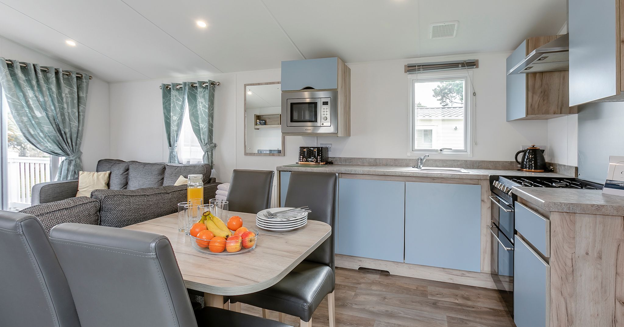 Modern kitchen and living area with dining table, fruits, and grey furniture