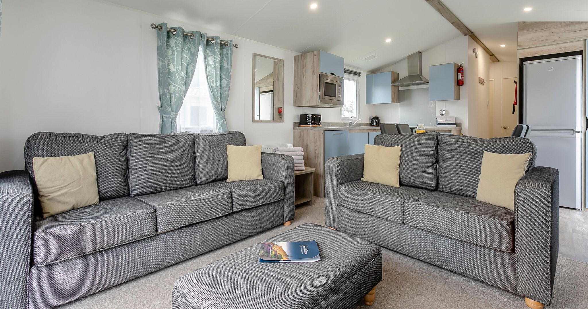 Modern open-plan living room and kitchen with two grey sofas and a matching ottoman