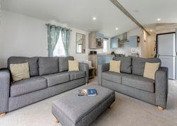 Modern open-plan living room and kitchen with two grey sofas and a matching ottoman