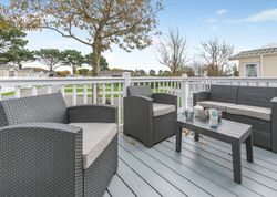 Outdoor patio with grey wicker furniture and a coffee table on a deck