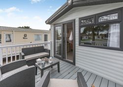 Outdoor deck area with wicker seating and a coffee table outside a mobile home