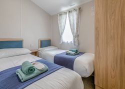 Twin bedroom with two single beds, blue headboards, and folded towels on each bed.