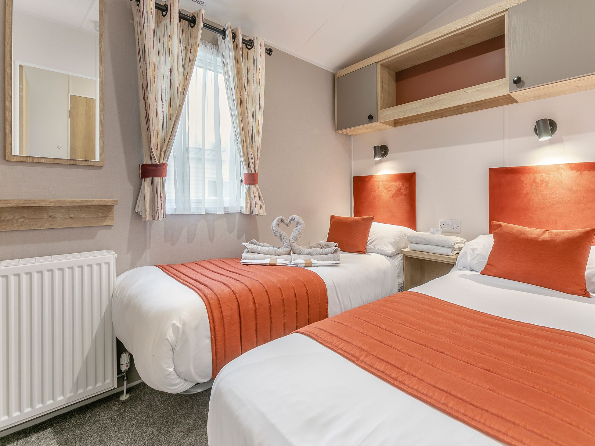 Modern twin bedroom with orange accents and neatly arranged beds