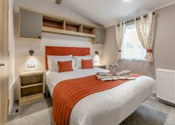 Modern hotel bedroom with orange accents and towel swans on bed