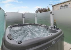 Outdoor hot tub with bubbling water, glasses, and a bottle of champagne