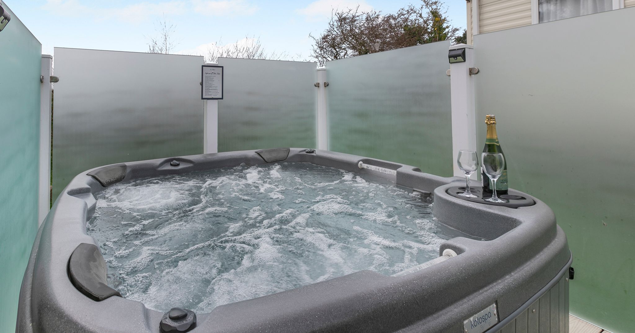 Outdoor hot tub with bubbling water, glasses, and a bottle of champagne