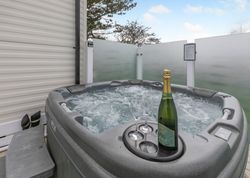 Outdoor hot tub with a bottle of sparkling wine and two glasses on the edge