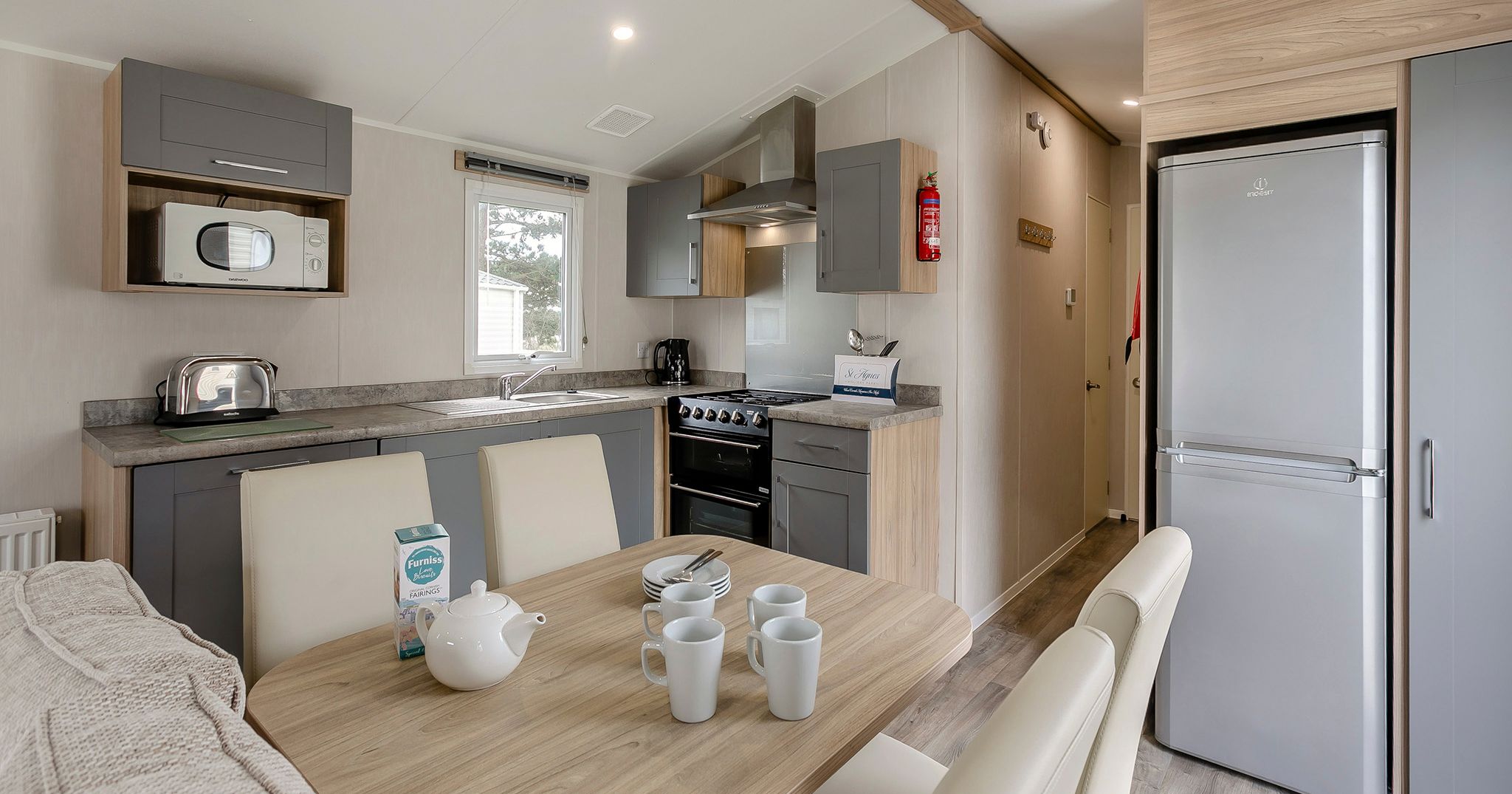 Modern kitchen and dining area in a compact living space with table set for tea