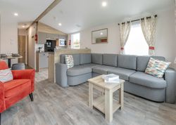Modern living room with grey sectional sofa, red armchair, and open kitchen.